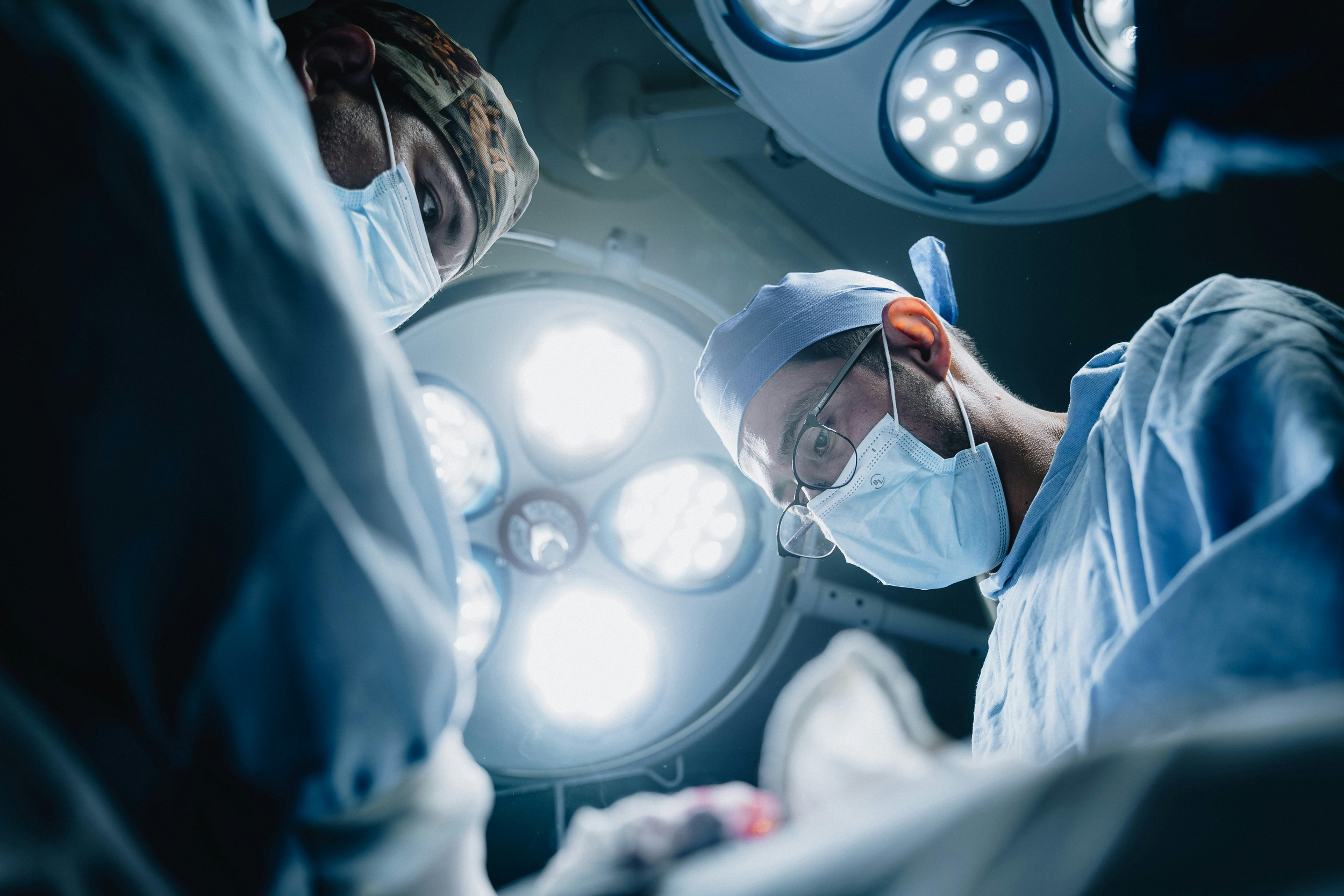 Medical professional suturing an injury on a person's arm with surgical instruments