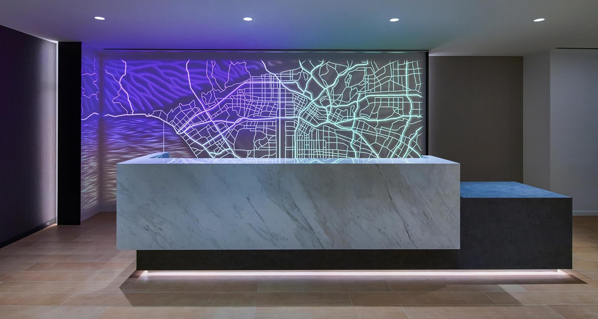 A stylish bar with a backlit feature wall that depicts a map design with different color lights.