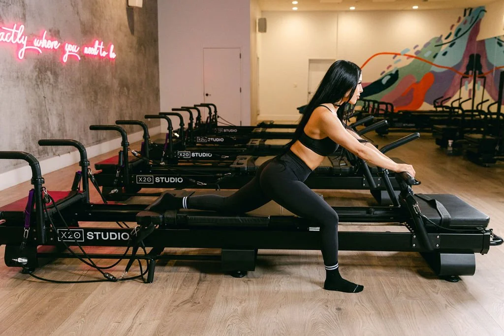 Instructor giving hands-on adjustments during an XFormer Pilates class