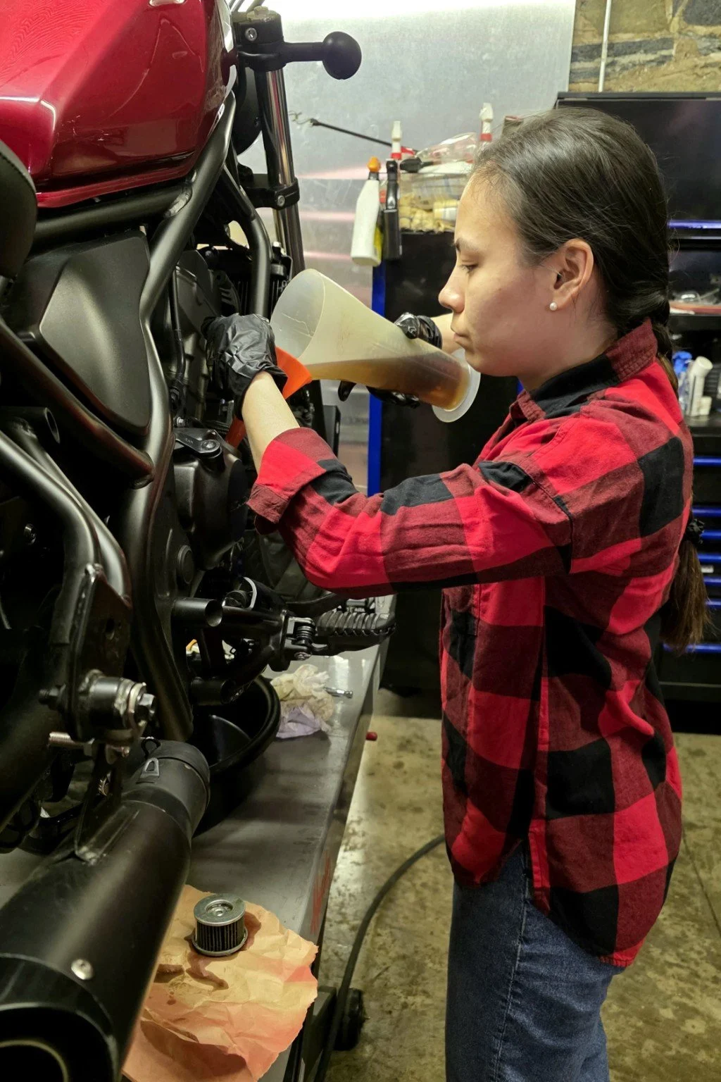 Participant adding oil to a motorcycle during maintenance