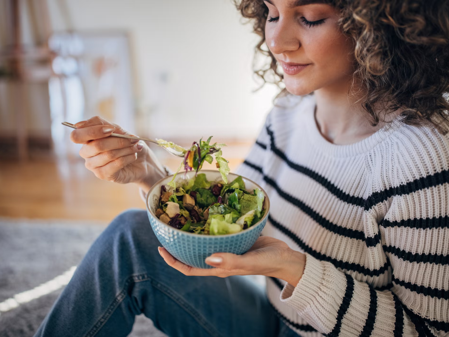 Woman eating a healthy salad representing nutrition and diet supporting gastrointestinal health and digestive wellness