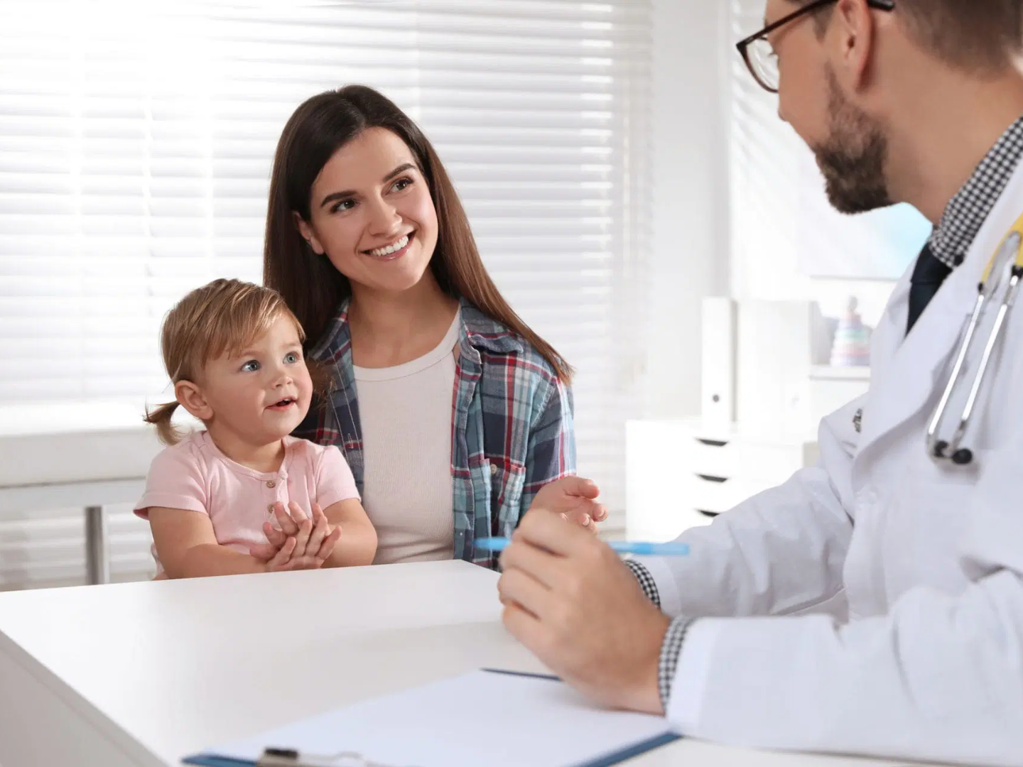 Mother holding a baby while speaking with a pediatric doctor during a child health consultation representing pediatric care and family medicine