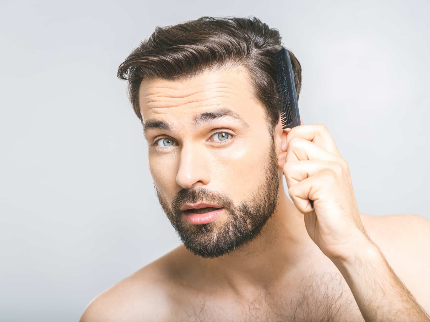 Man checking hairline with comb, representing early hair thinning and Alma TED hair restoration consultation
