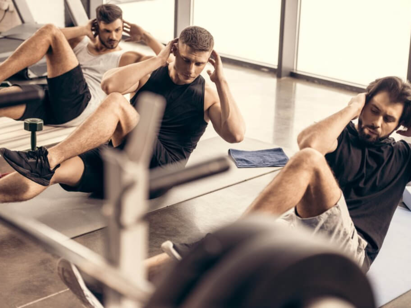 Men performing core exercises in a gym representing strength training and improved energy associated with testosterone therapy