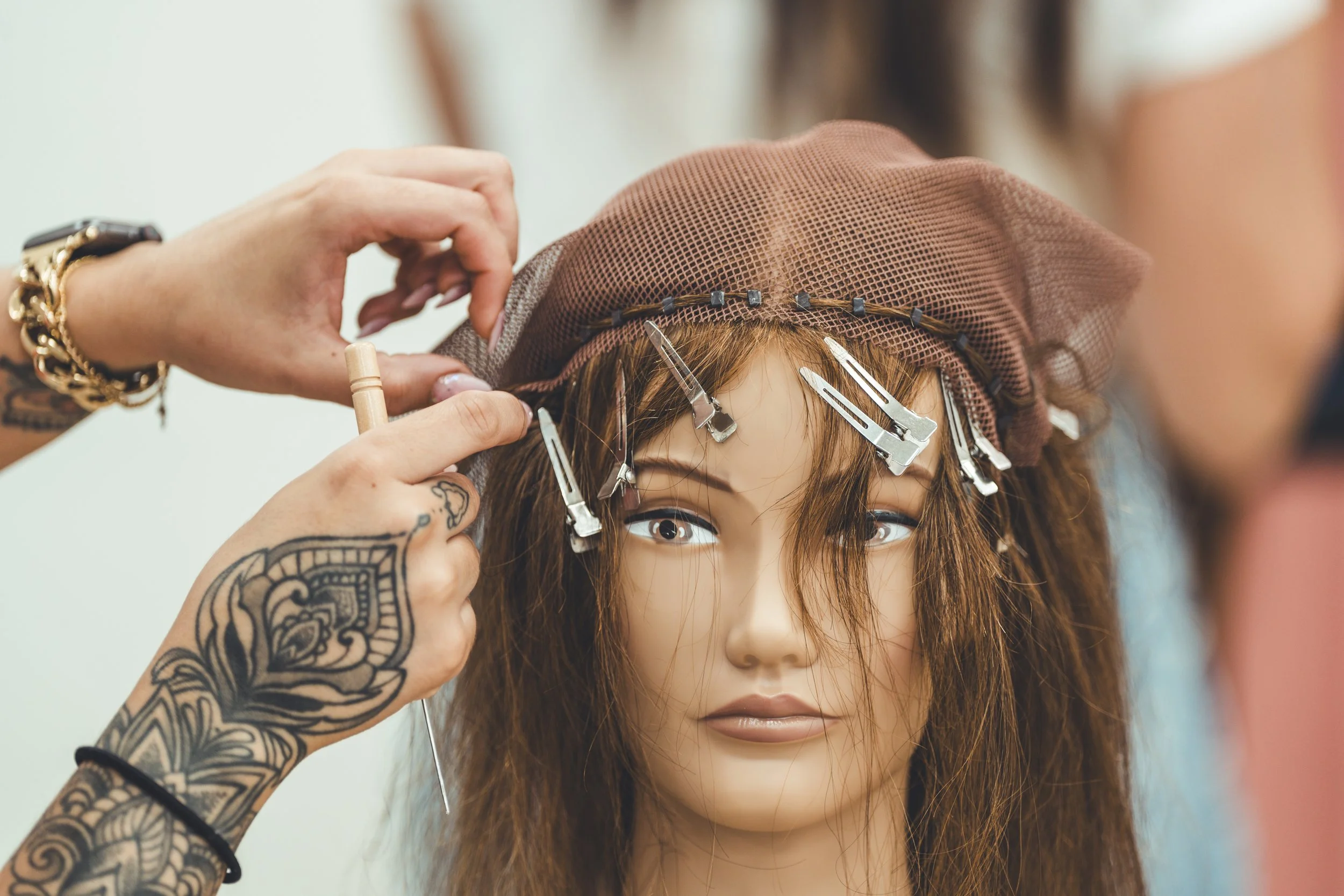 Close-up of hands working with a mesh foundation on a mannequin head