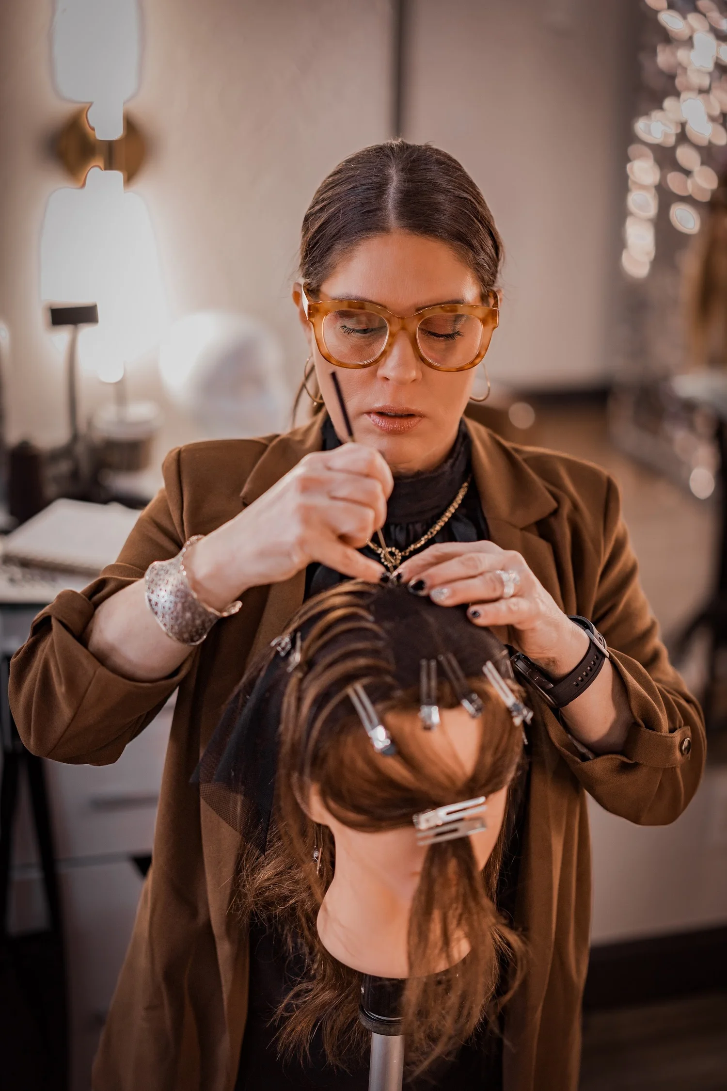 Close-up of a stylist sectioning and clipping a hair unit into place during hands-on foundation training