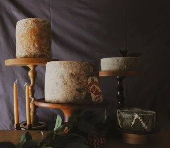 Whole cheese truckles on wooden cake stands with candles