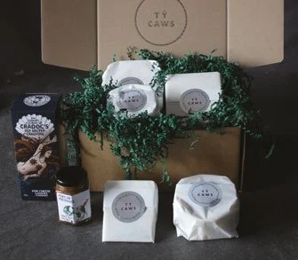 A Tŷ Caws Christmas cheese box with wrapped cheeses, chutney and crackers