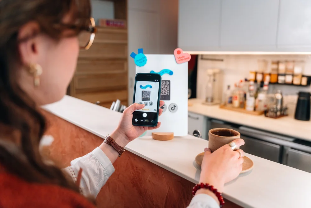 Cliente scannant Le Tag de Smiirl avec son smartphone au comptoir d'un café, photo produit par LUSANT Prod.