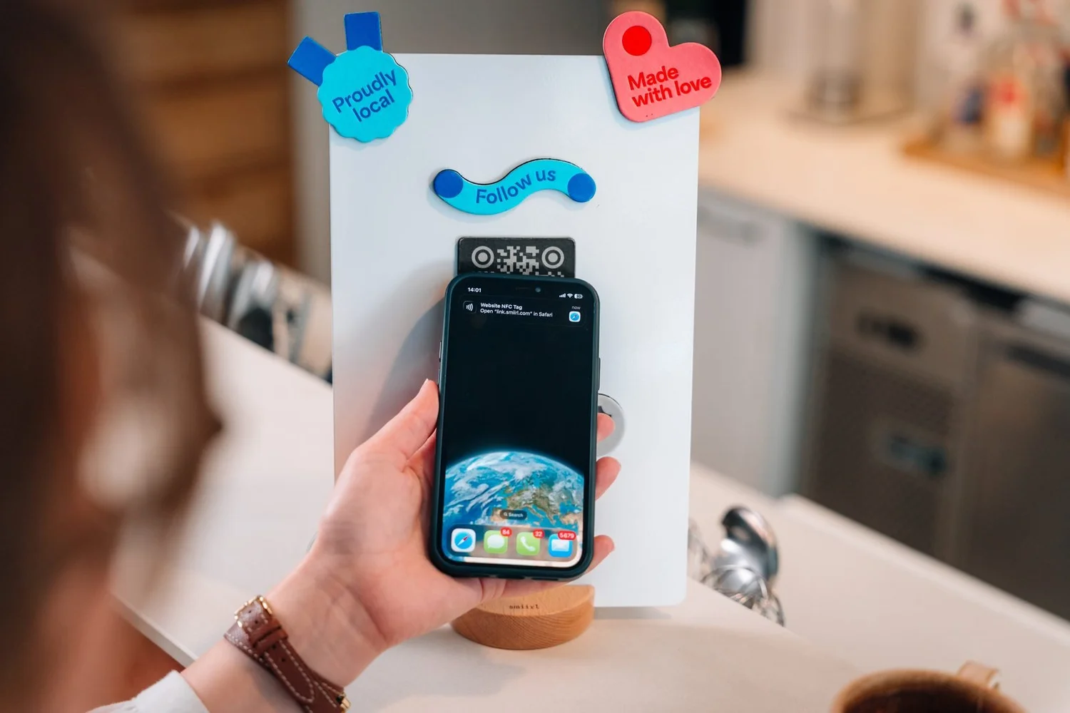 Cliente approchant son téléphone du présentoir connecté Smiirl sur le comptoir d'un café