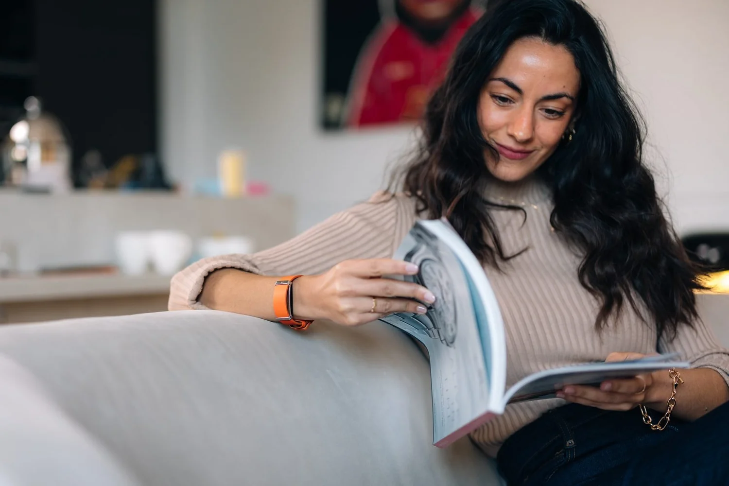 Femme lisant sur un canapé avec un bracelet connecté Fascine orange au poignet