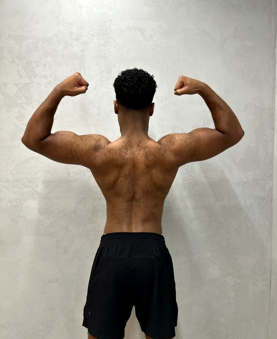 Rahman after 12 weeks of body recomposition training at Fortius Dubai — back double biceps pose
