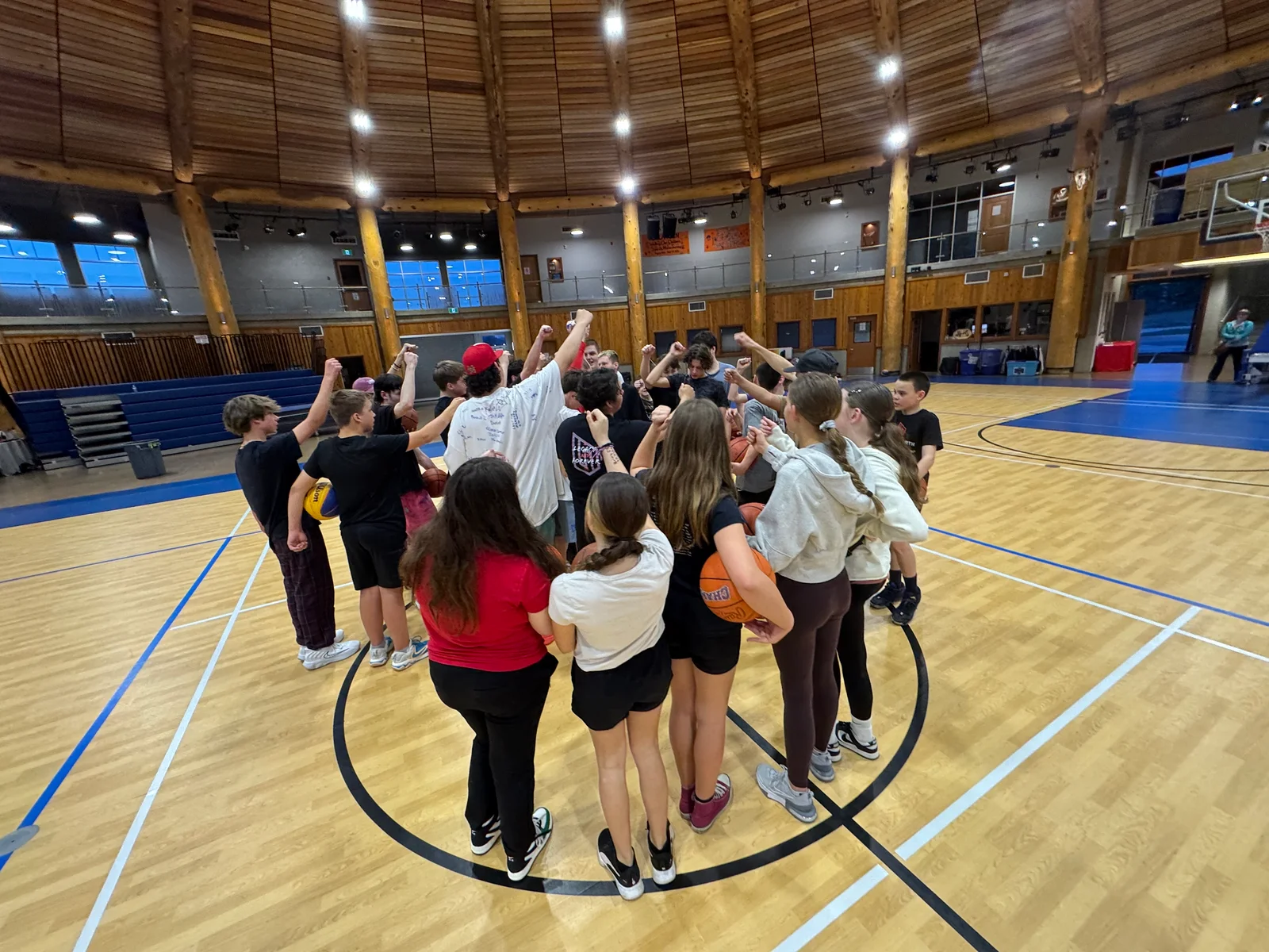 After Hours Hoops participants bring their hands together in a gym huddle