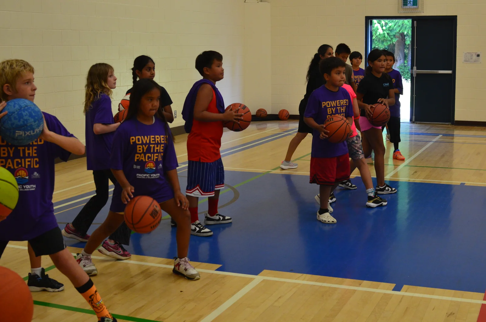 Young athletes practice with basketballs at the Pacific Youth Basketball and Wellness Summit