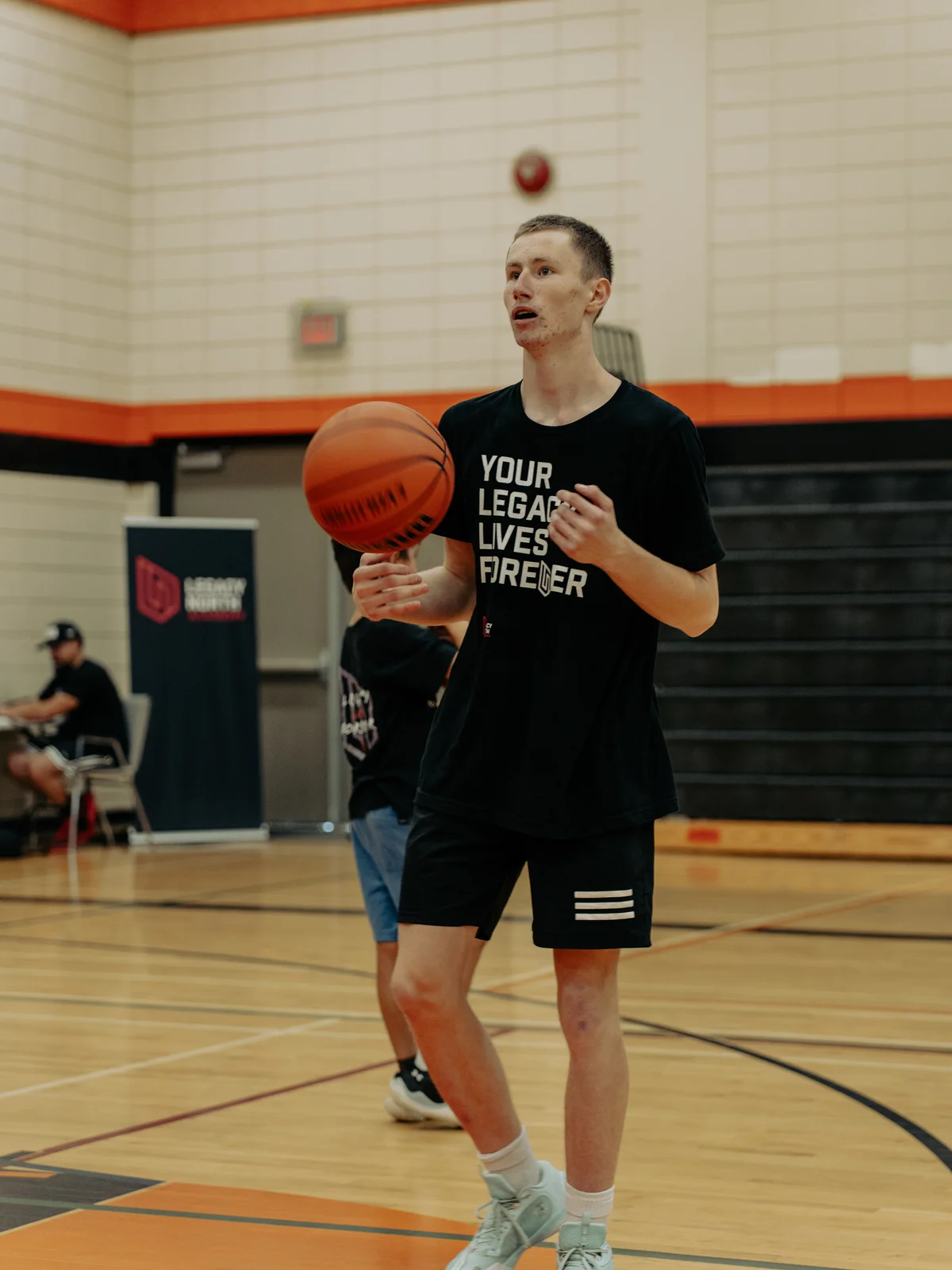 Kage Williams handling a basketball in his Your Legacy Lives Forever shirt