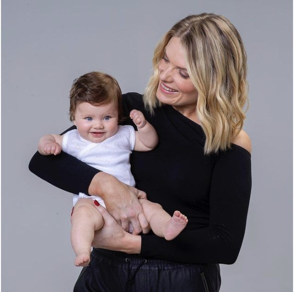 Erin Molan holding a baby wearing the By Erin singlet