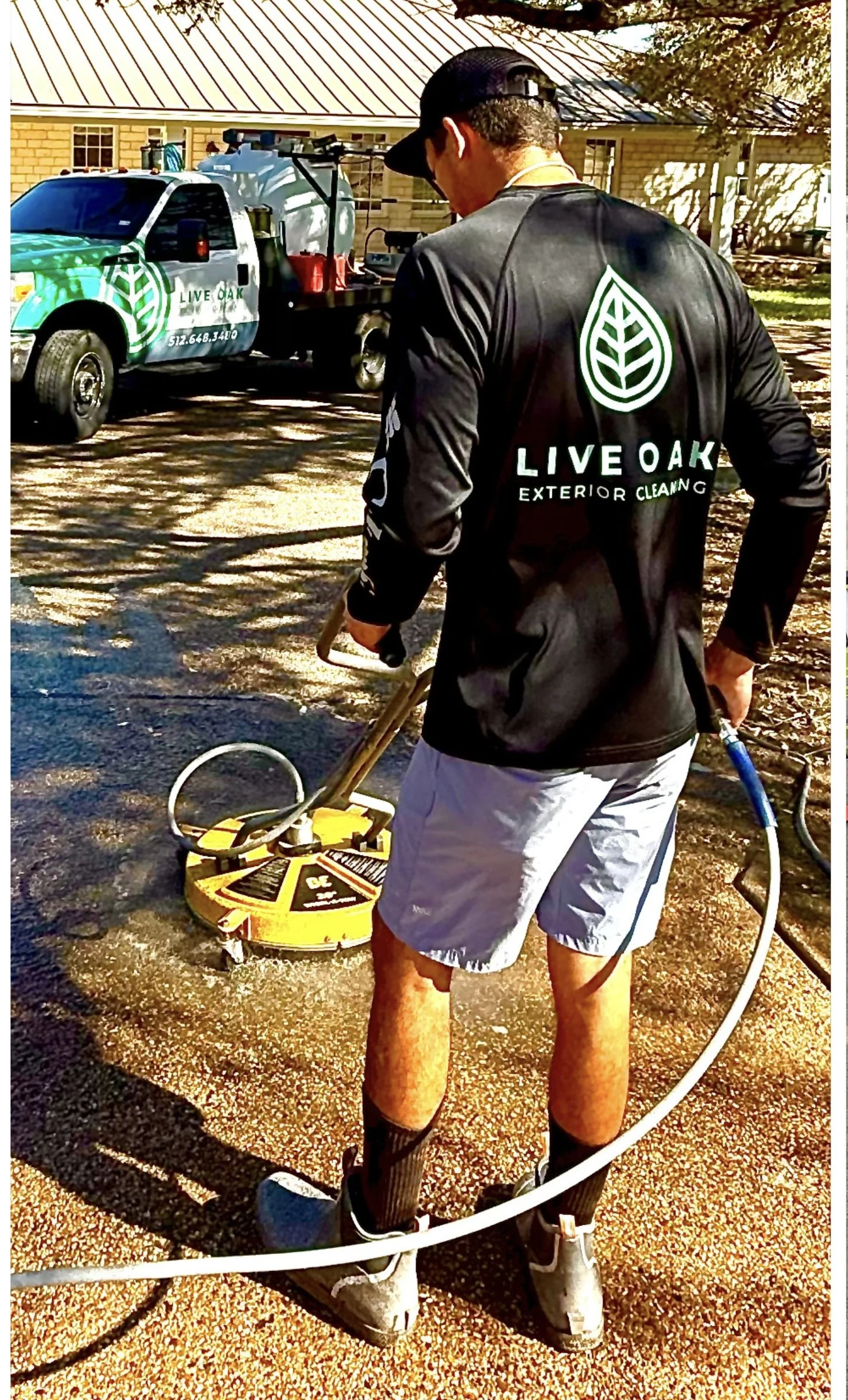 Jared Barker, owner of Live Oak Exterior Cleaning, using a surface cleaner on a driveway in Dripping Springs, TX