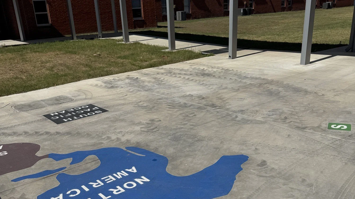 Construction tire marks across a white top playground surface at a Blanco ISD school before cleaning