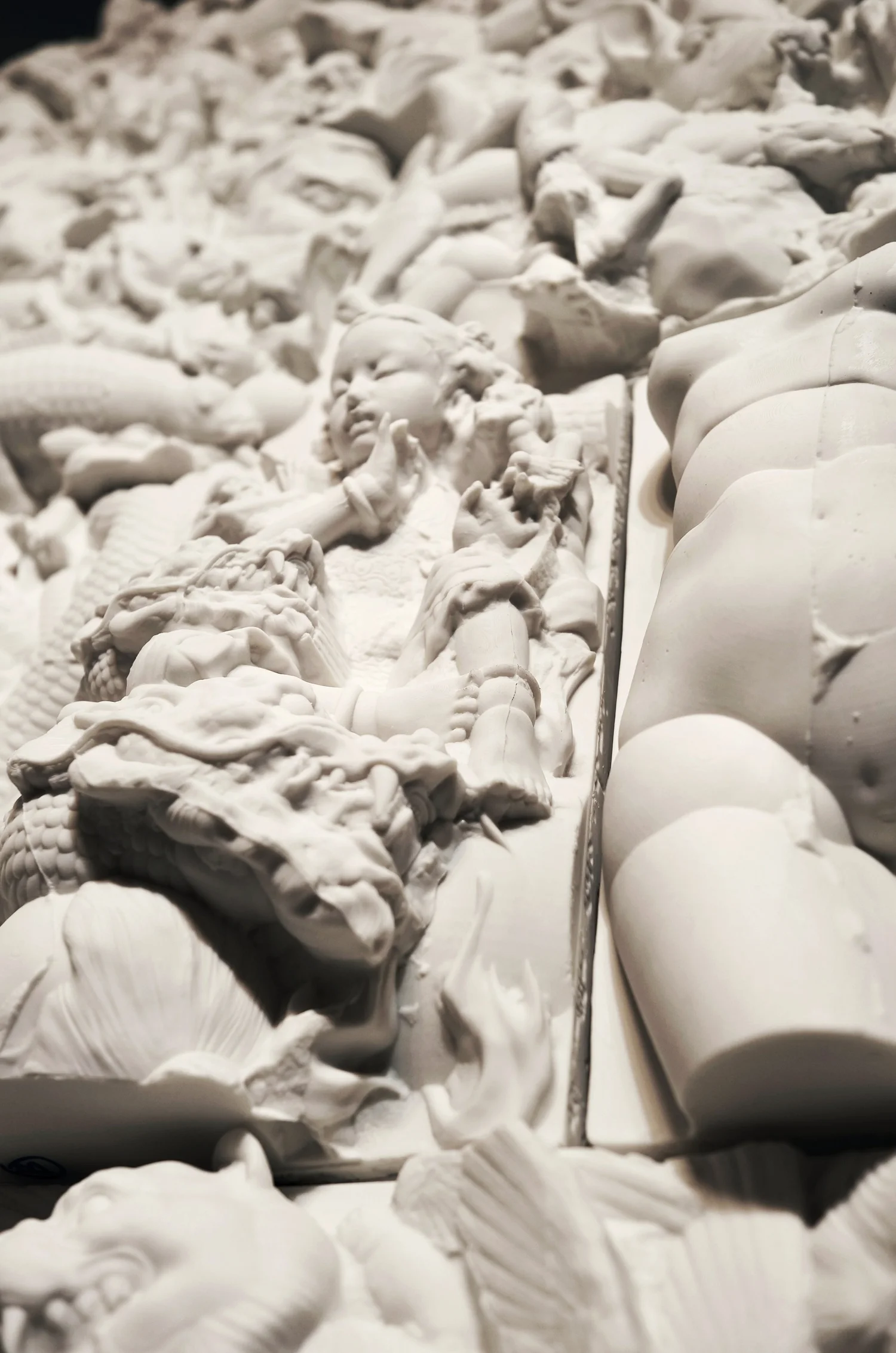 Oblique close-up of white ceramic figures and raised relief.