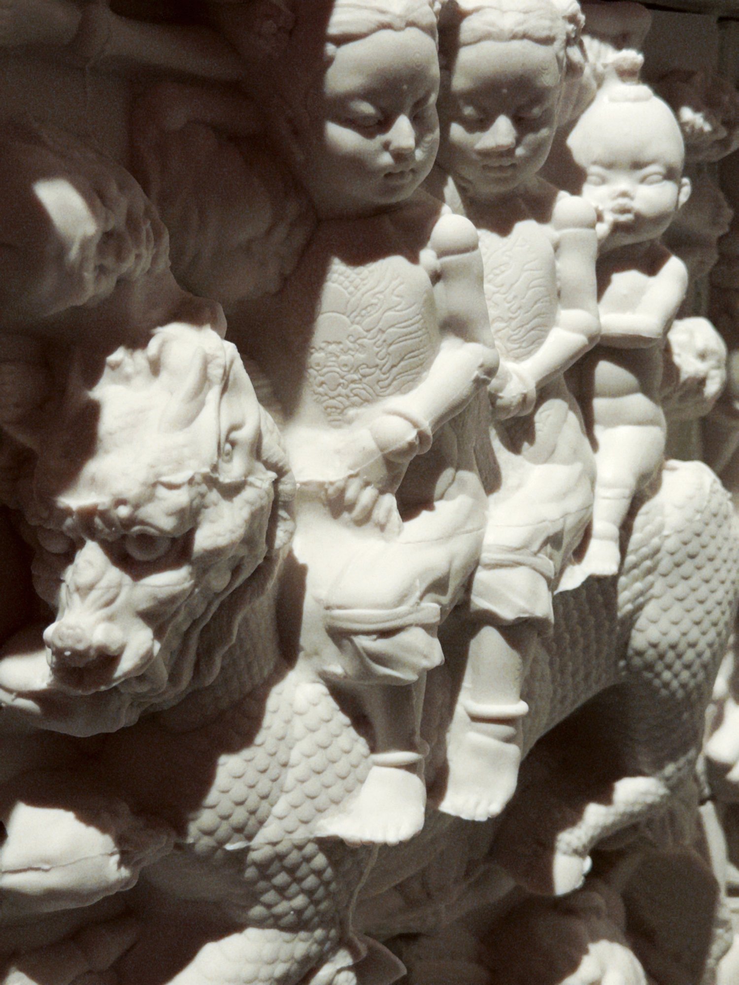 Close-up of small ceramic figures amid surrounding relief forms.