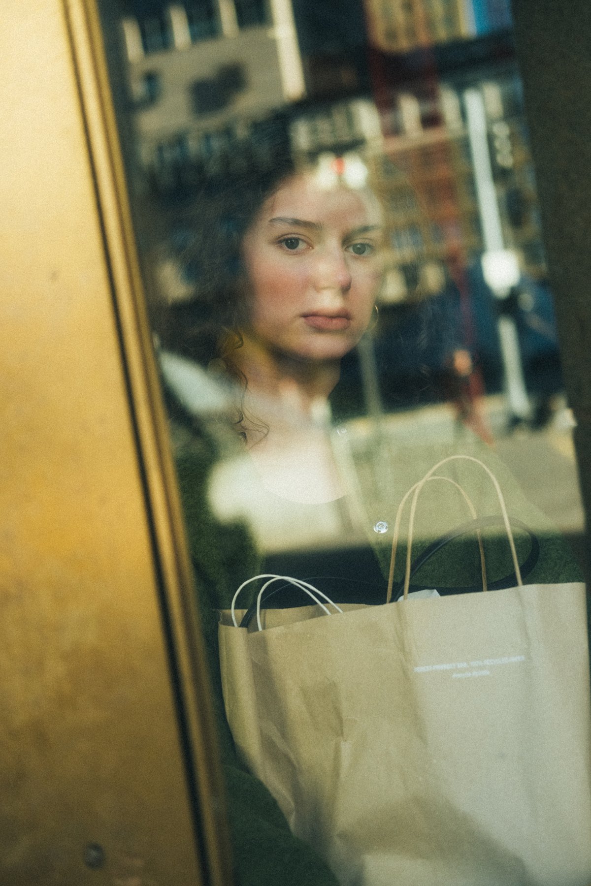 Olenka seen through a window layered with reflections of buildings