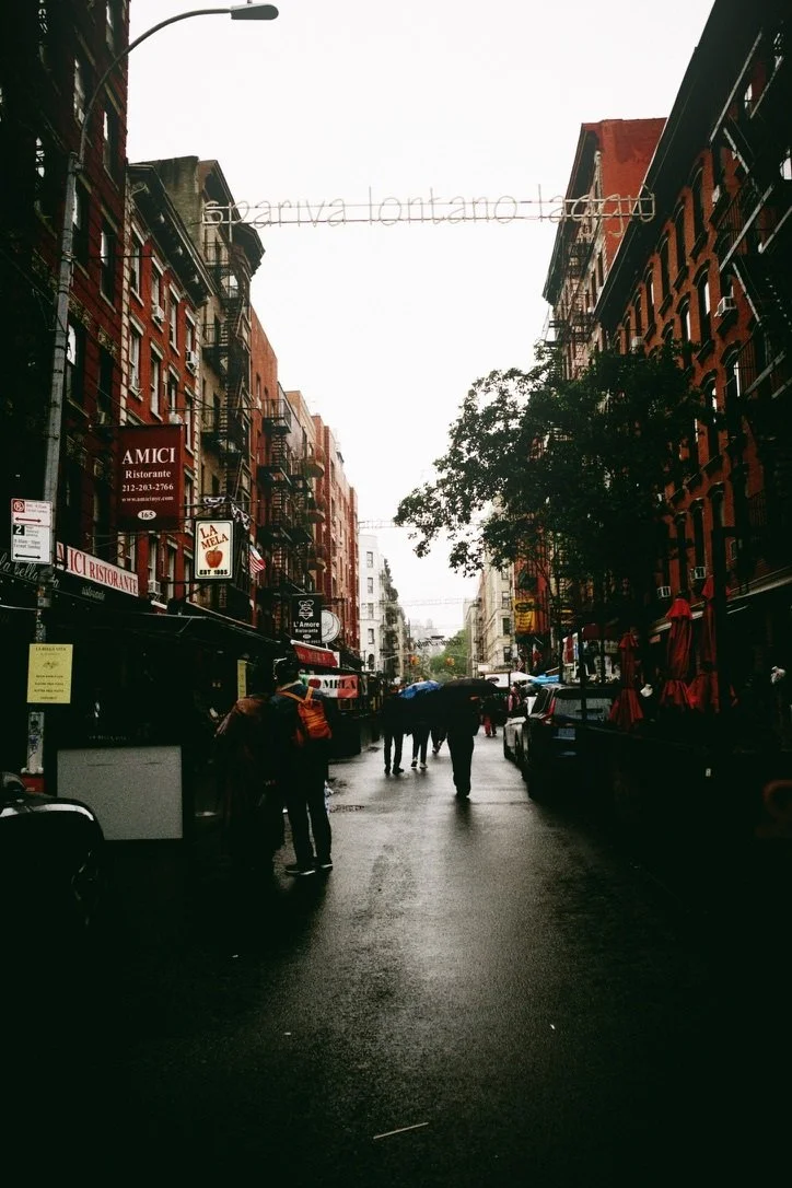 Rain-wet street with reflections and signs for Amici and La Mela