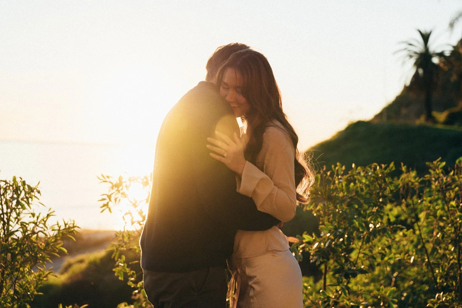 Hannah and Garrett embracing in warm low sunlight