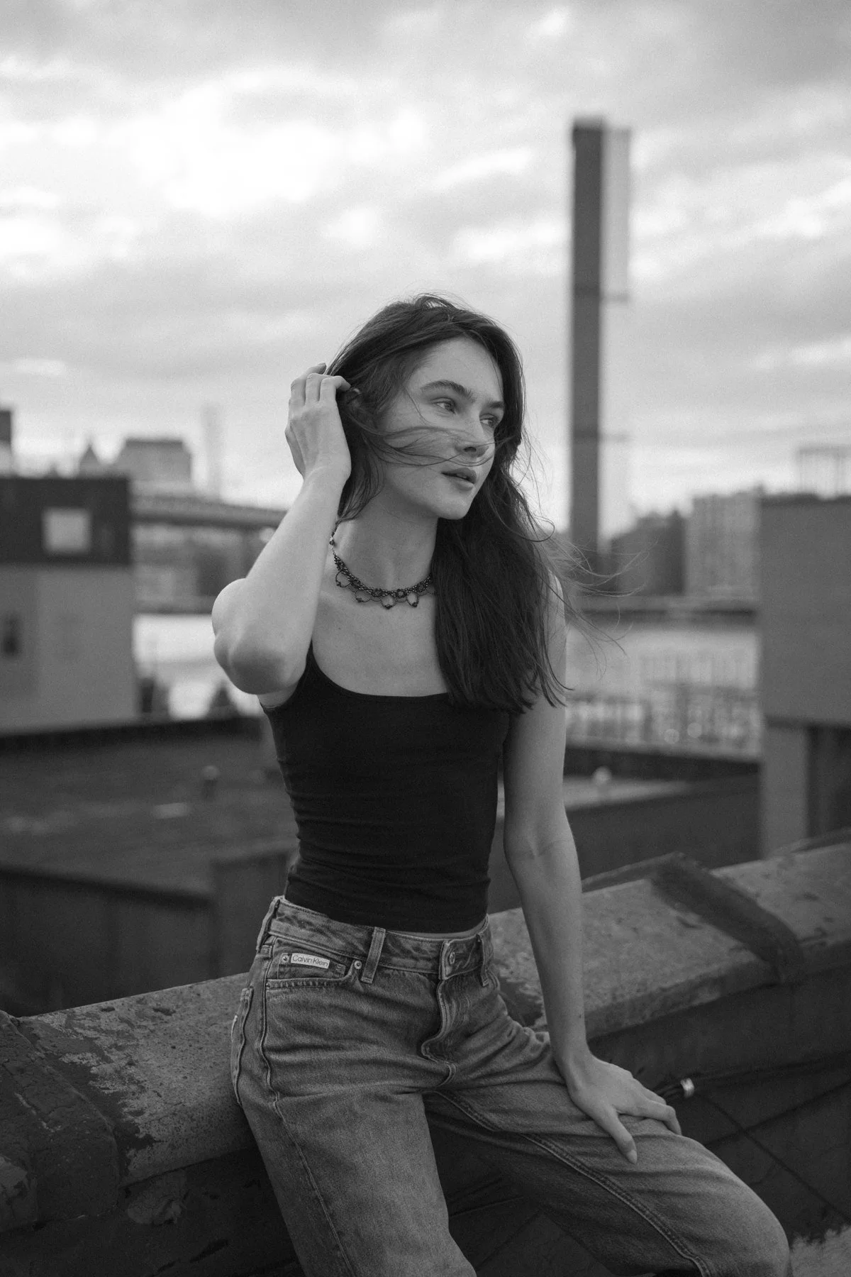 Black-and-white portrait of Amanda seated at a rooftop ledge
