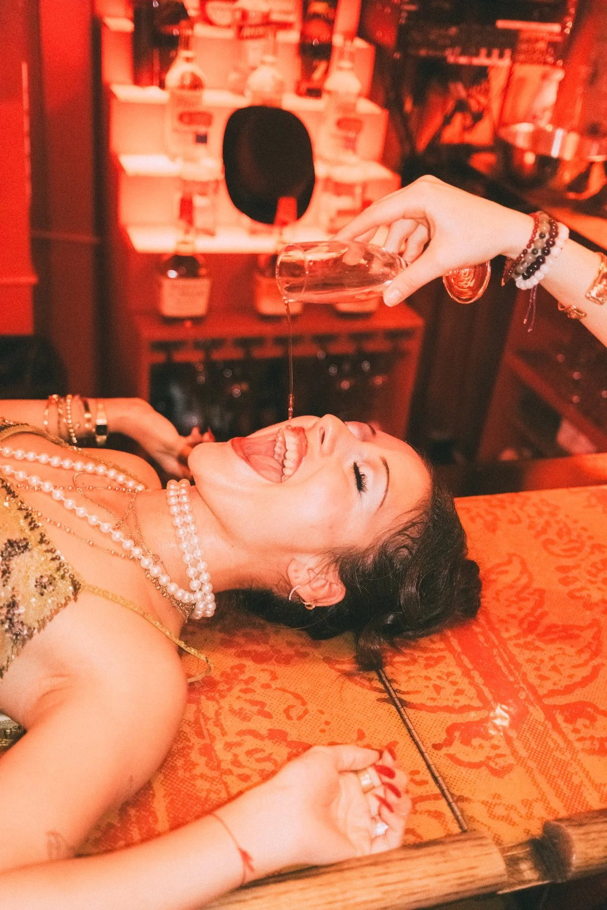 Close angled portrait of Eden reclining on the bar beneath red light