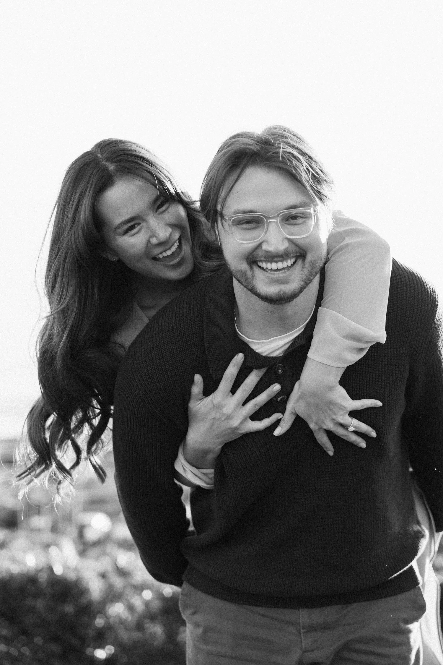 Black-and-white portrait of Hannah and Garrett laughing during a piggyback moment