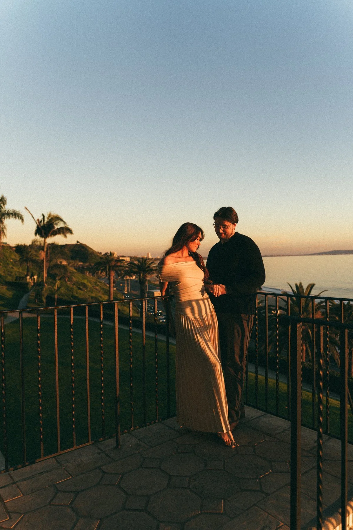 Hannah and Garrett standing together on a balcony beneath a wide sky