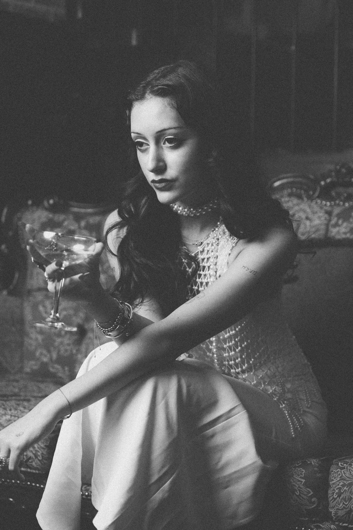 Black-and-white portrait of Eden seated on a patterned sofa