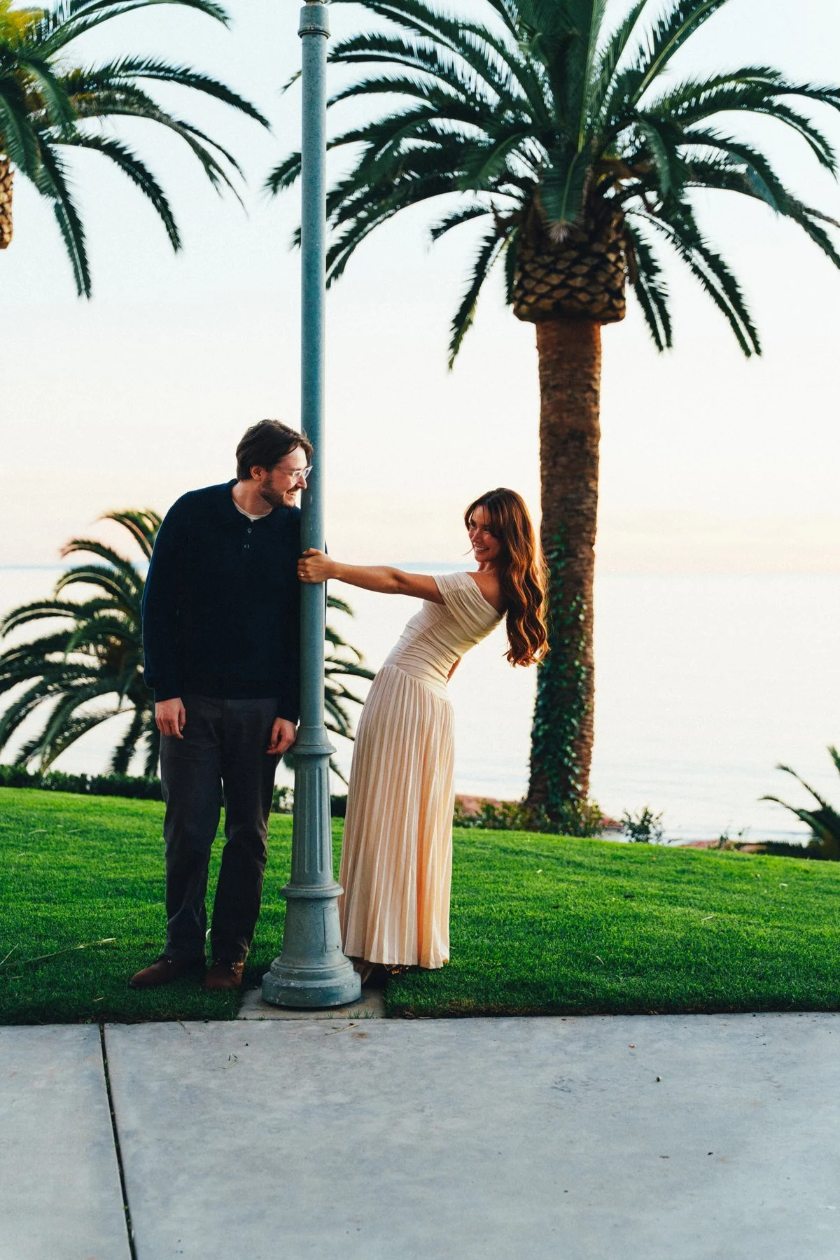 Hannah and Garrett standing beneath palms beside the coast