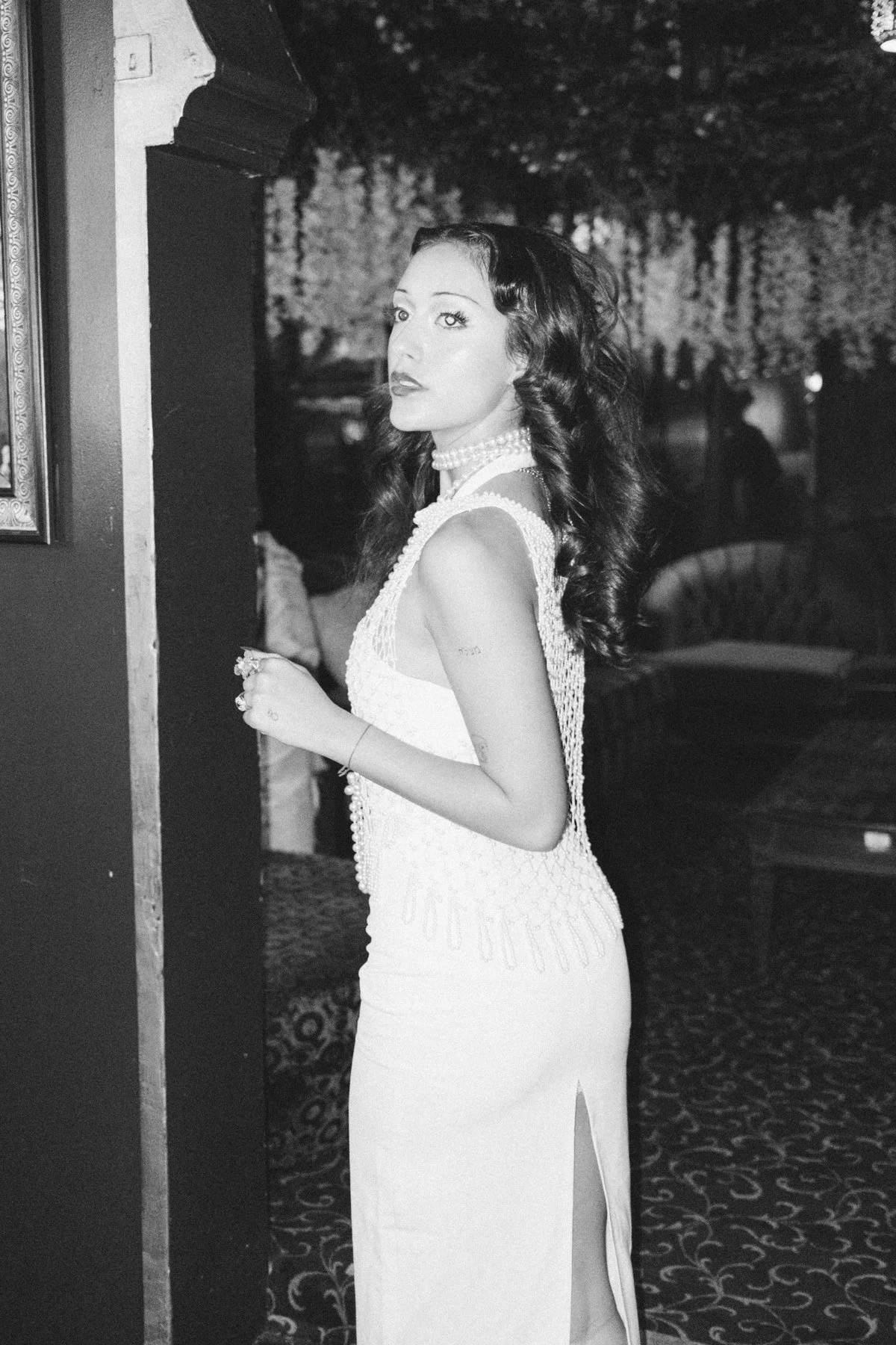 Black-and-white portrait of Eden turning toward the camera beside a doorway
