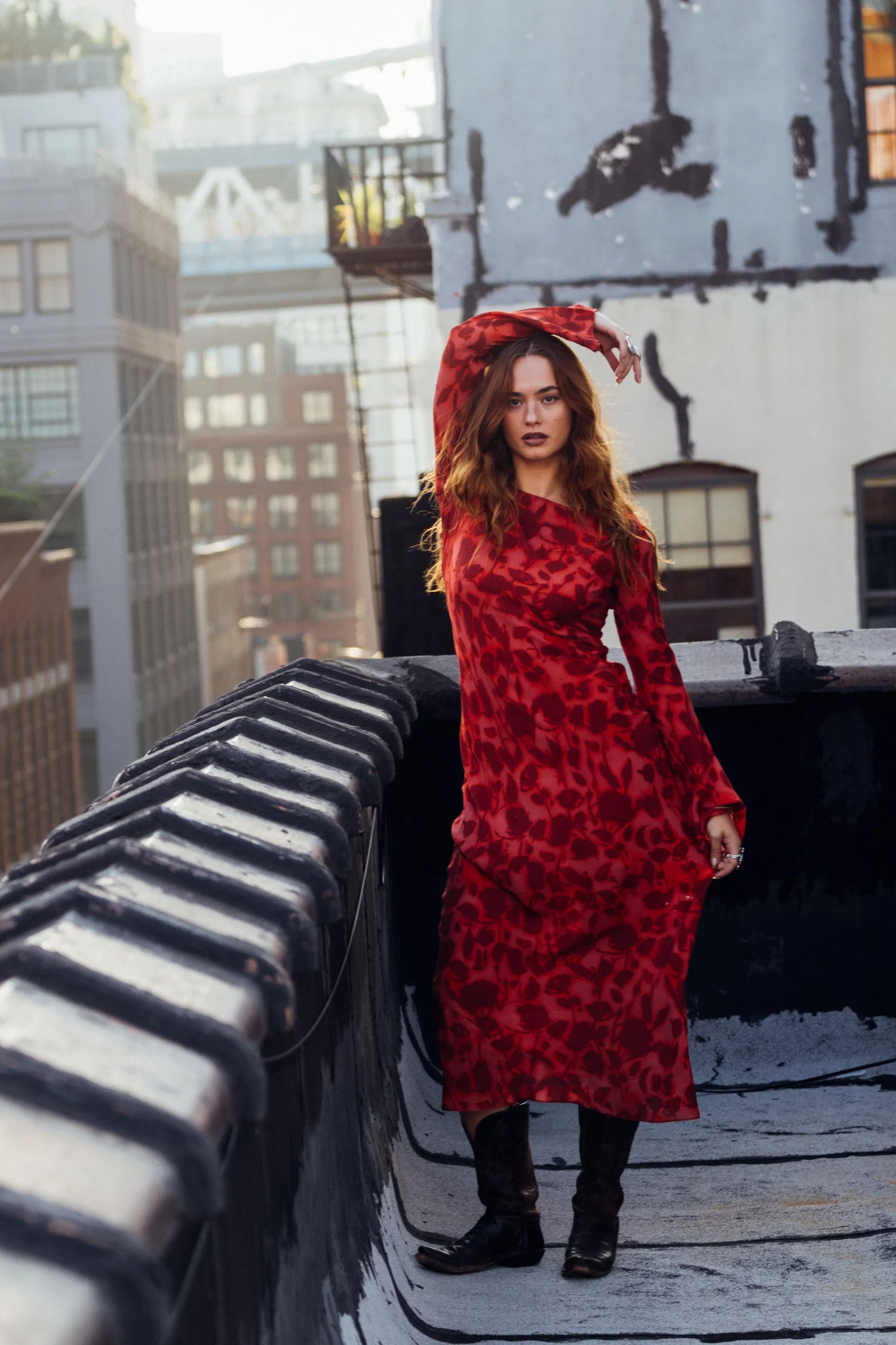Johnny in a red patterned dress beside a weathered rooftop parapet