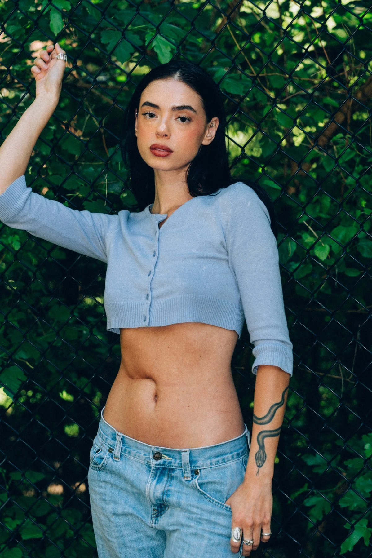 Hannahbeth standing against green leaves in a blue cardigan