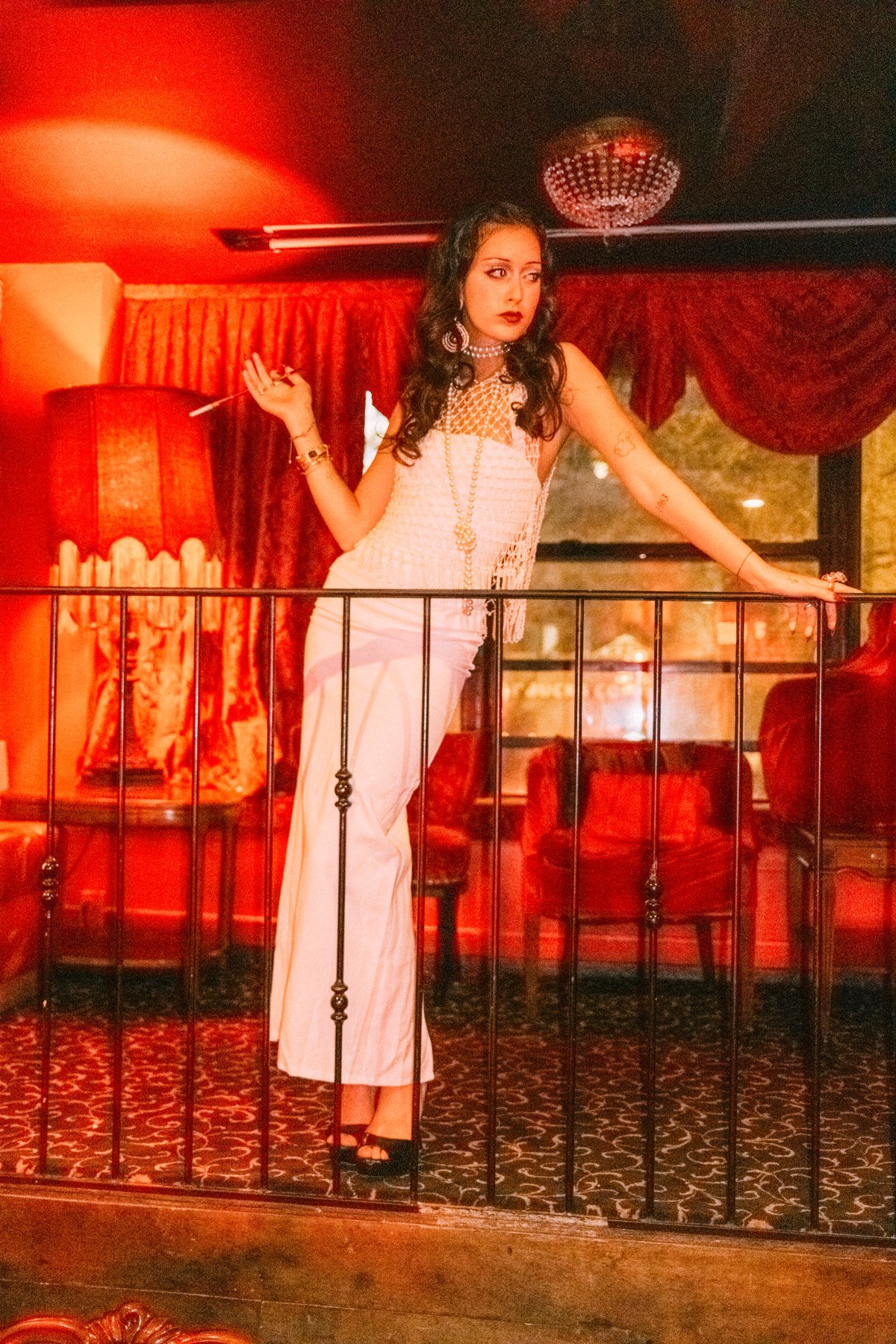 Full-length portrait of Eden in a white dress behind a dark railing