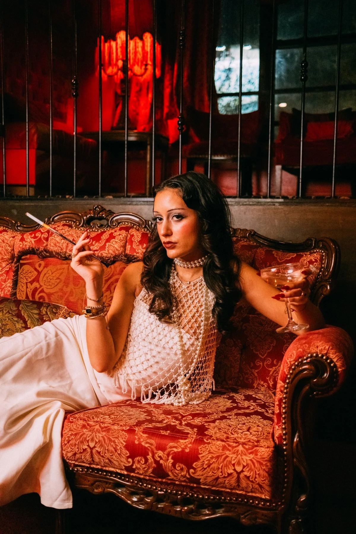 Eden seated closer in the frame on a patterned couch beneath red lanterns