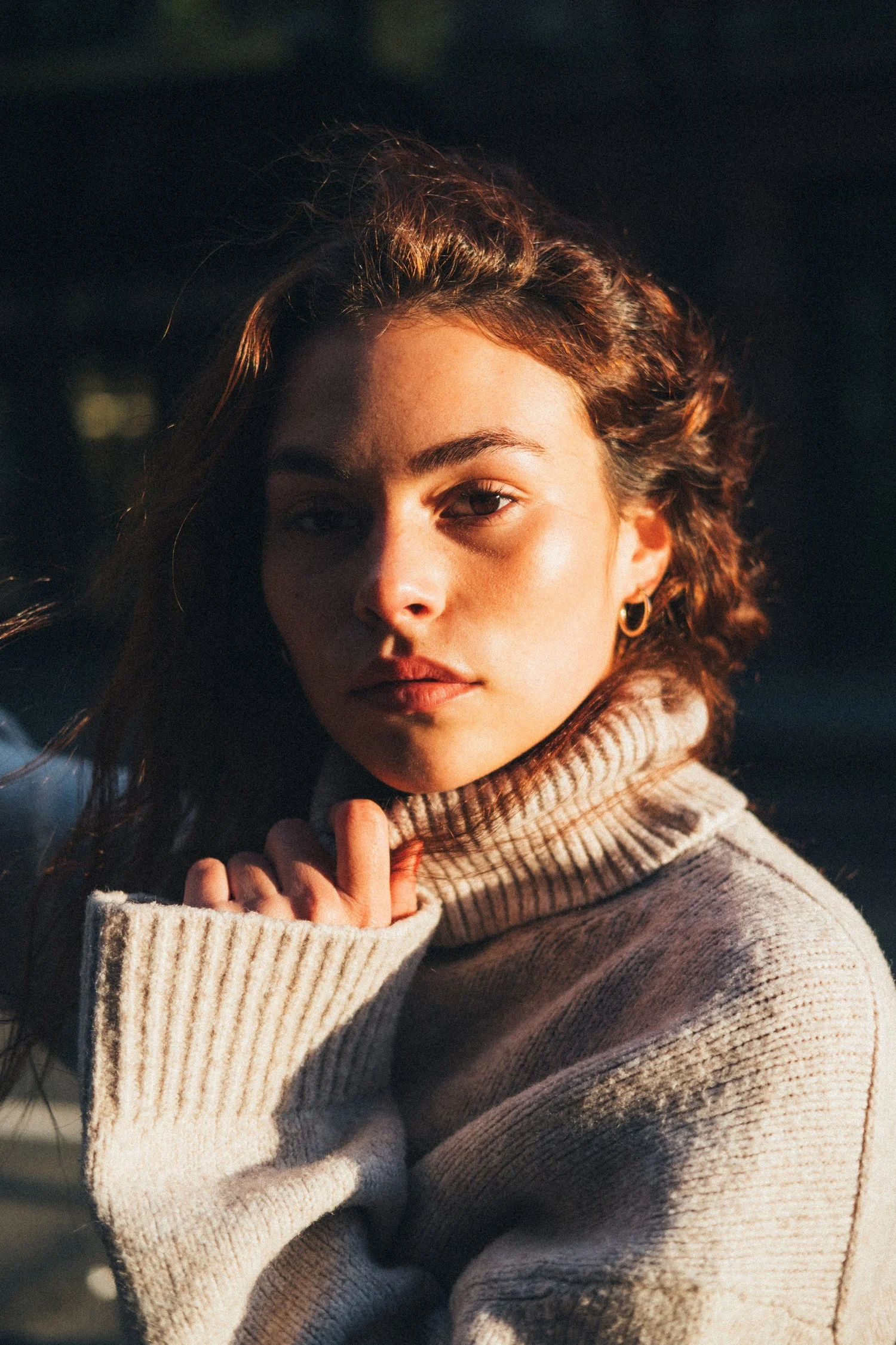 Close portrait of Marley in a cream turtleneck with sunlight on one side of her face.
