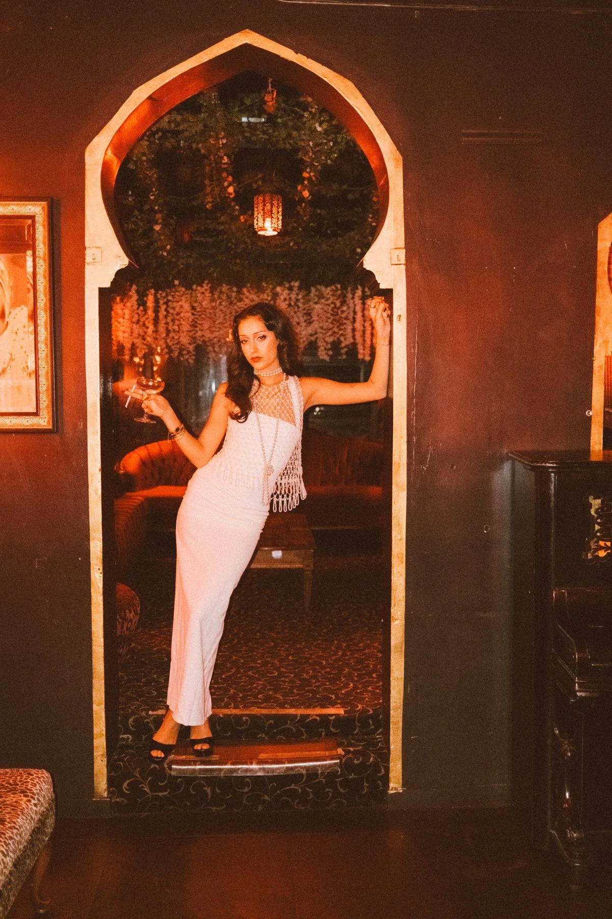 Eden standing in a pale dress and dark tights inside an ornate arch-shaped frame