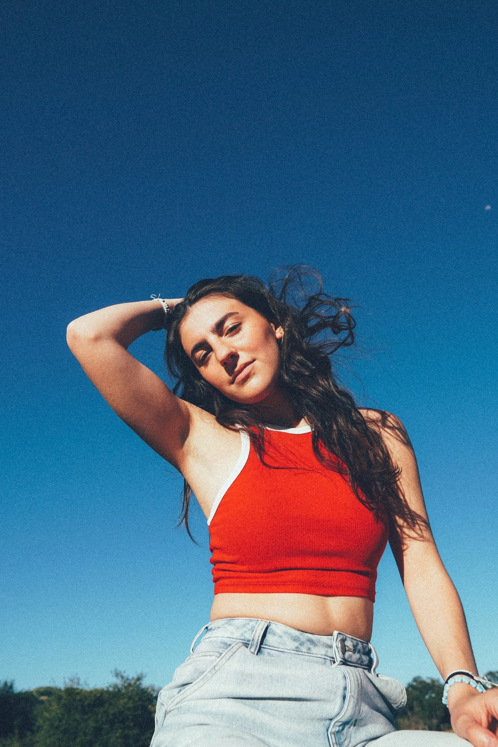 Low-angle portrait of Avery Lynch in a red top against a deep blue sky.