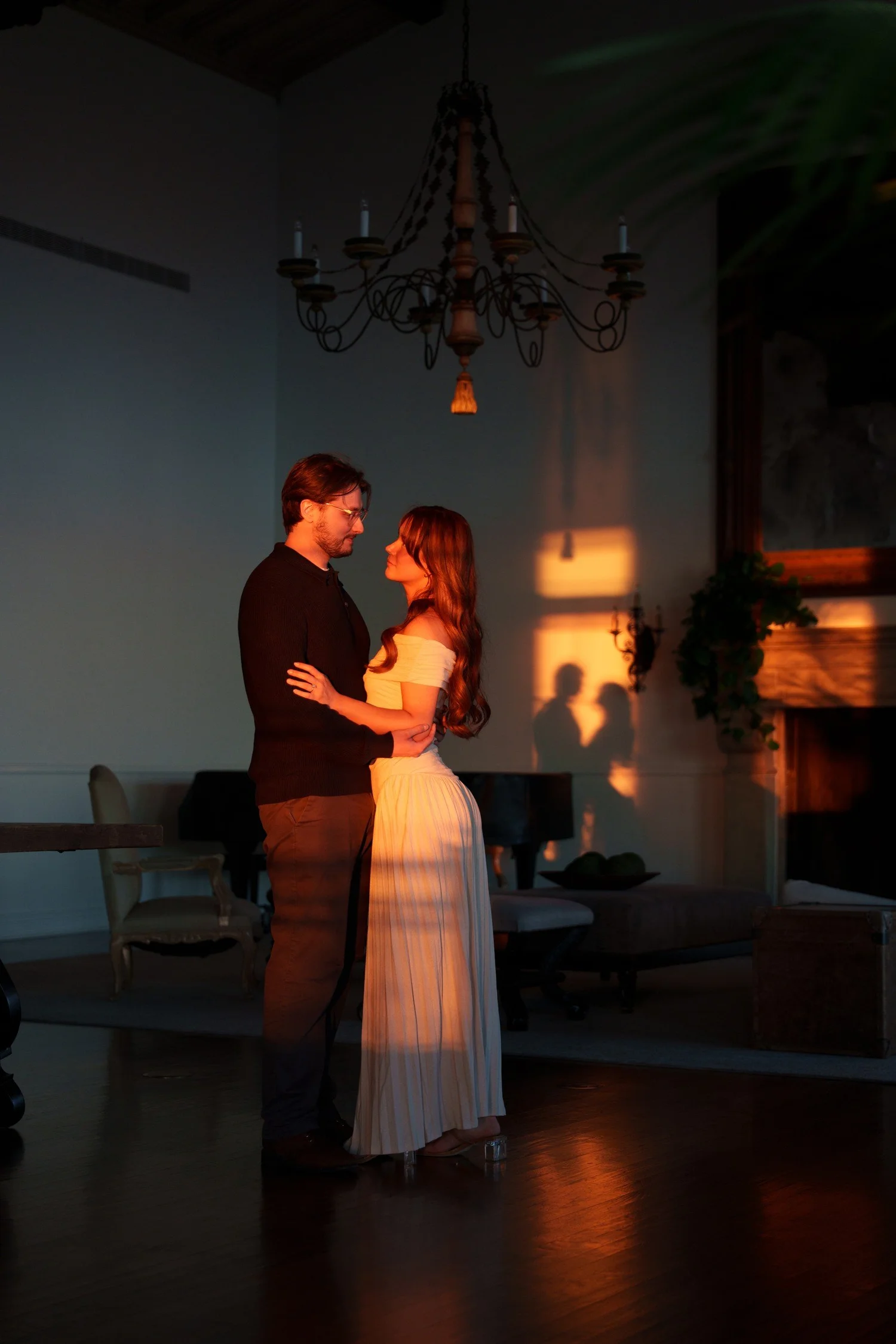 Hannah and Garrett in a dark interior with a patch of warm light