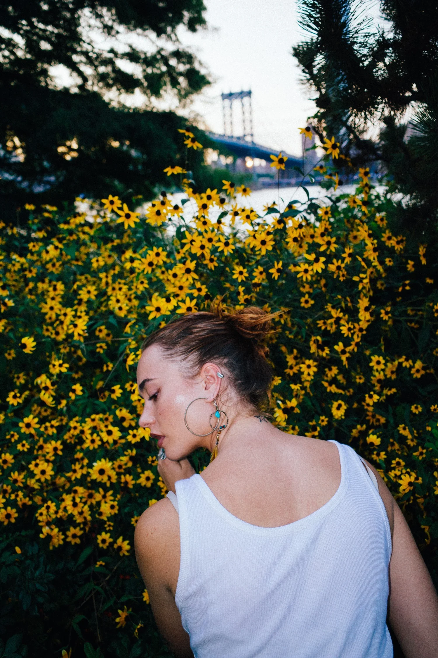Johnny turning beside yellow flowers with trees and a bridge in the background