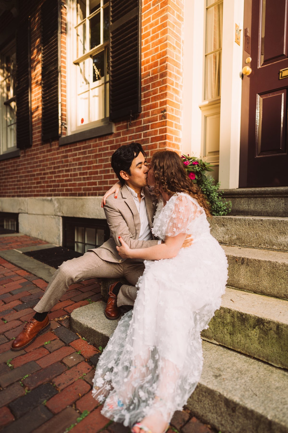 Stefano and Maddy kissing while seated on brick steps