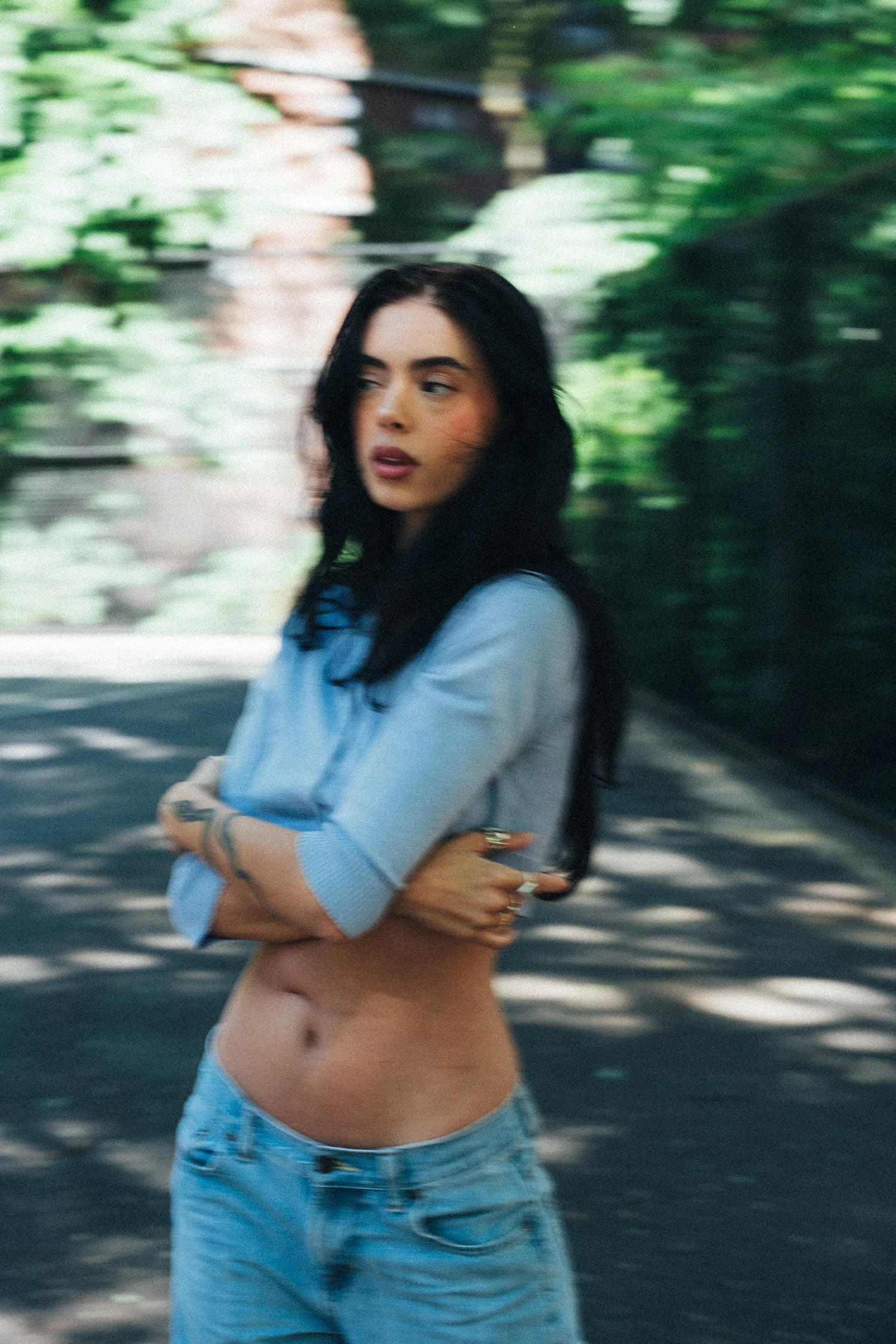 Hannahbeth in a blue cardigan with motion-blurred greenery behind her