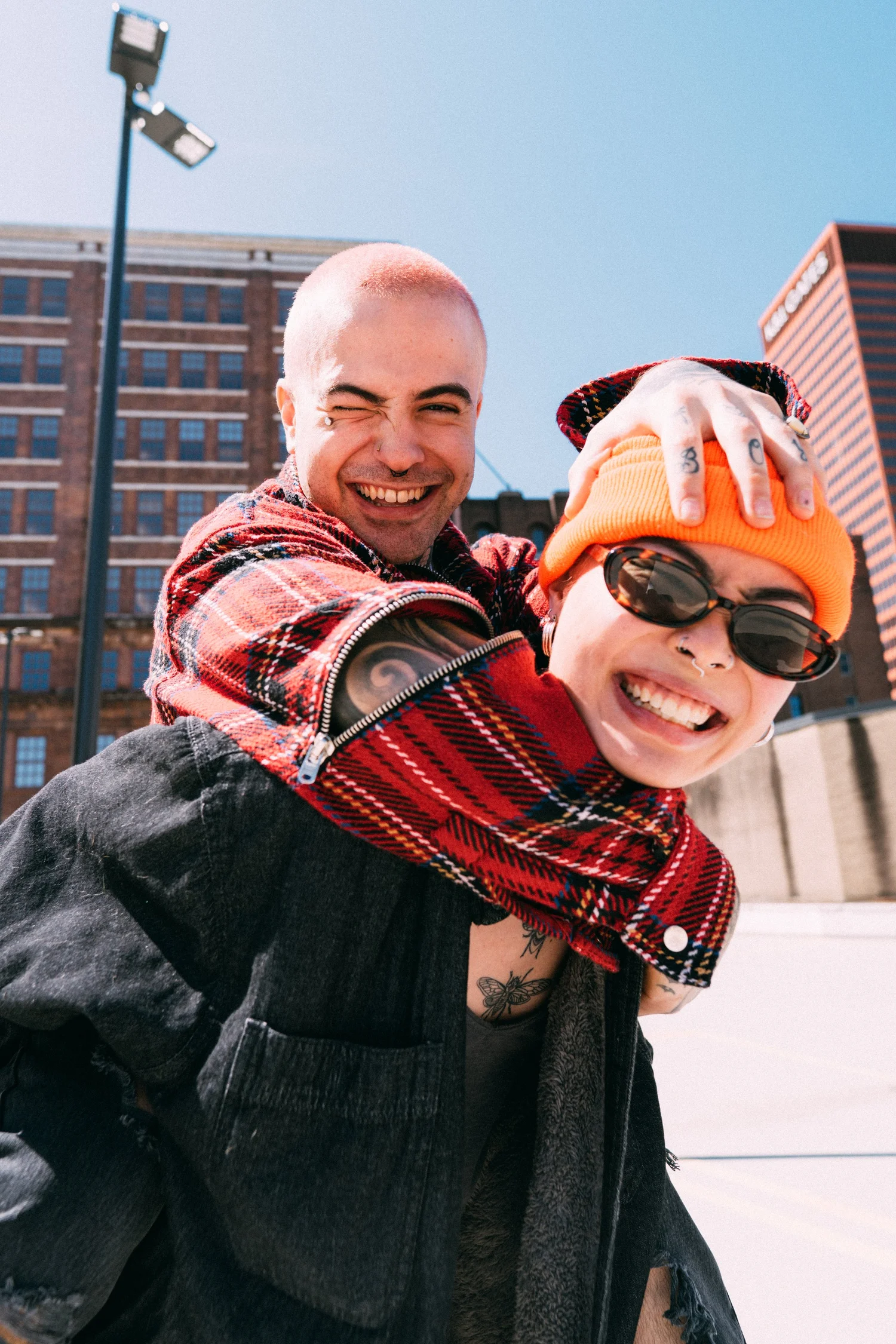 Ash and AJ laughing together during a piggyback portrait in bright sunlight