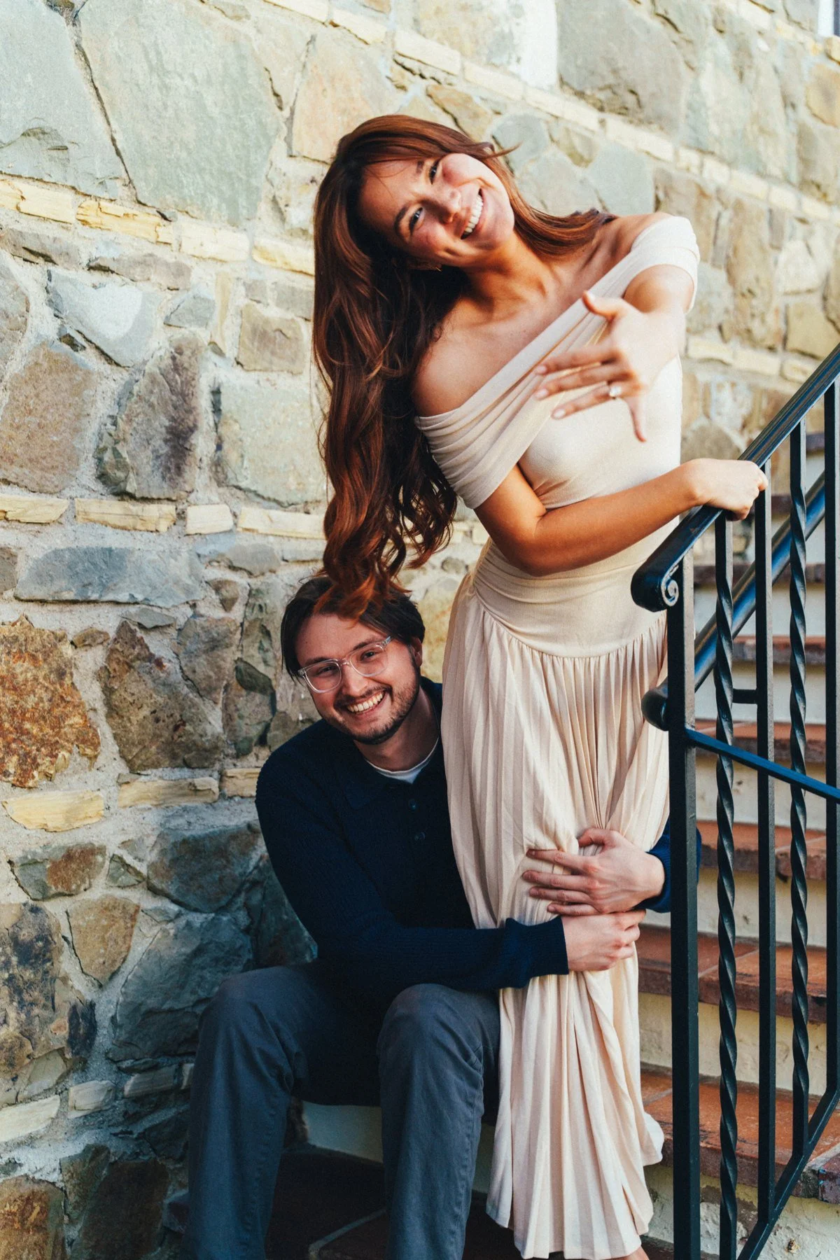 Hannah and Garrett laughing together on stone steps