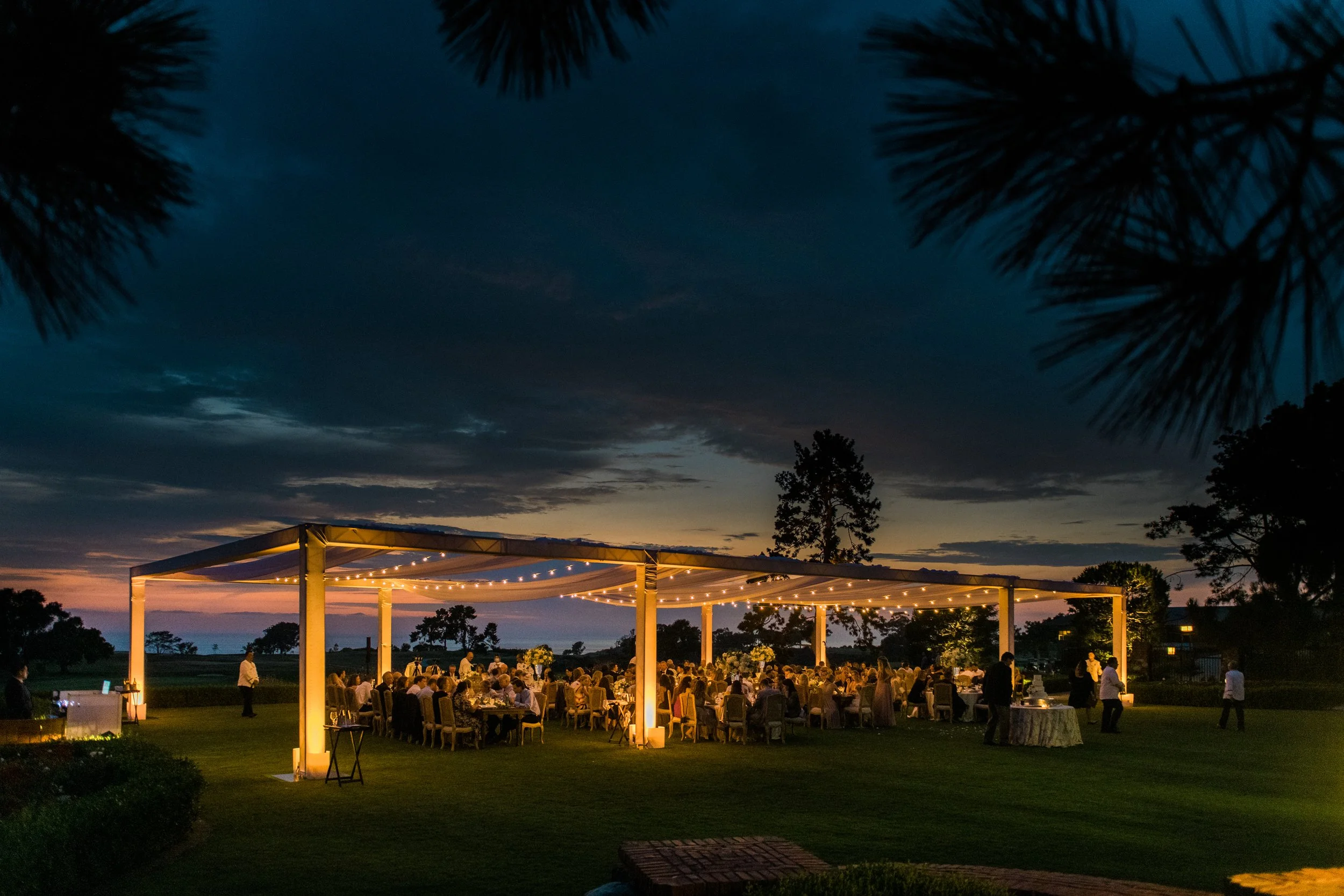 Outdoor wedding reception with paper lanterns and market lights at blue hour