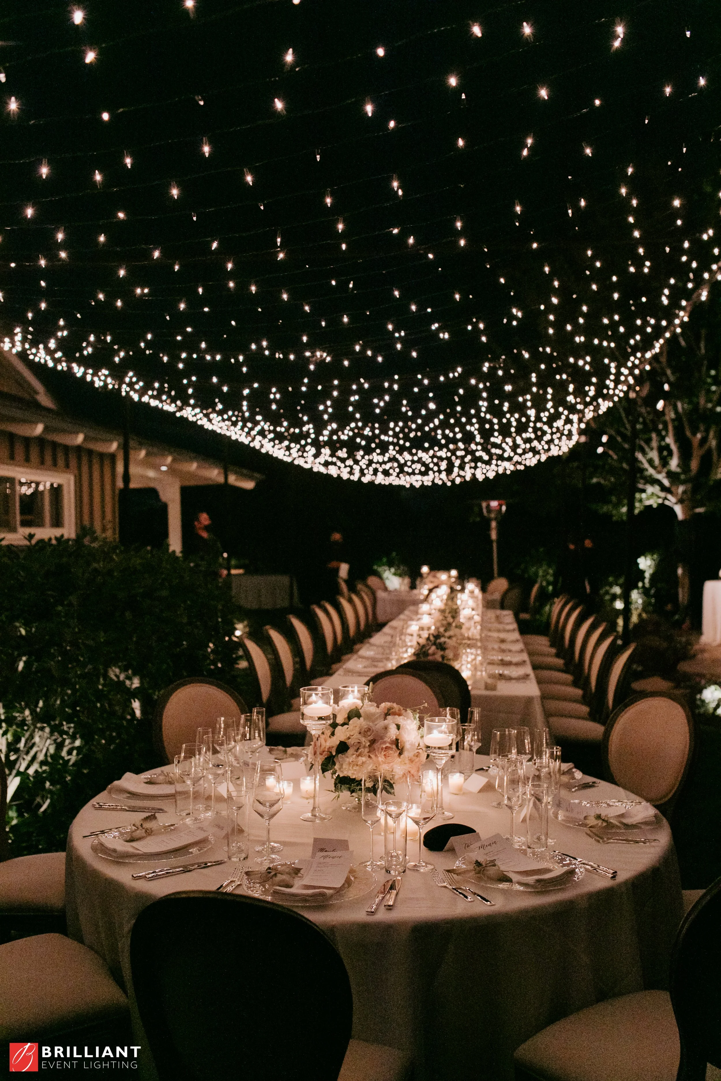 Twinkle light canopy over elegant outdoor wedding dinner