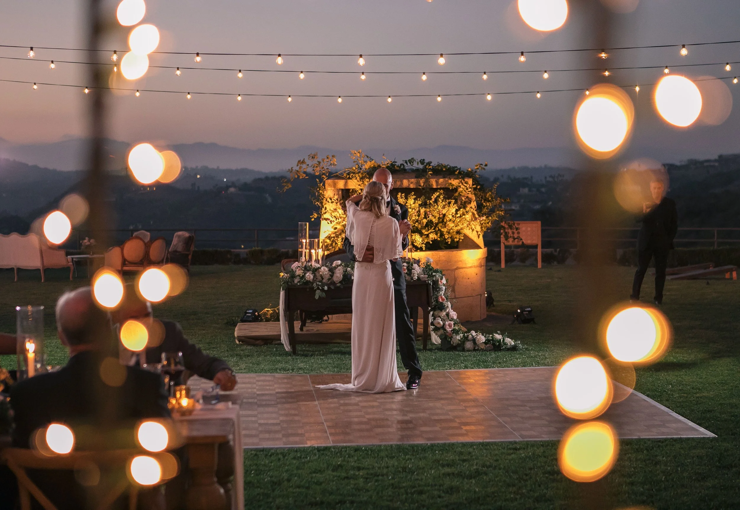 Bride and groom under black market light strands at night